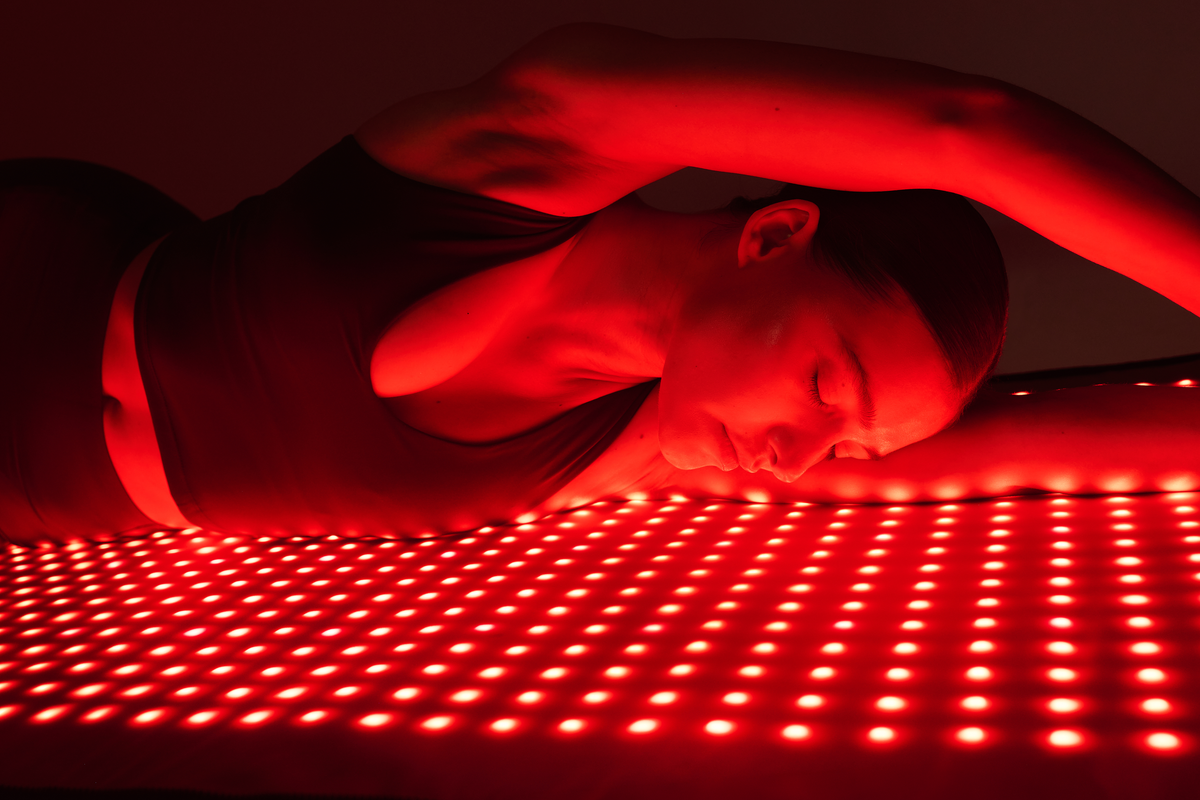 Woman resting on an illuminated Restora red and infrared light therapy mat