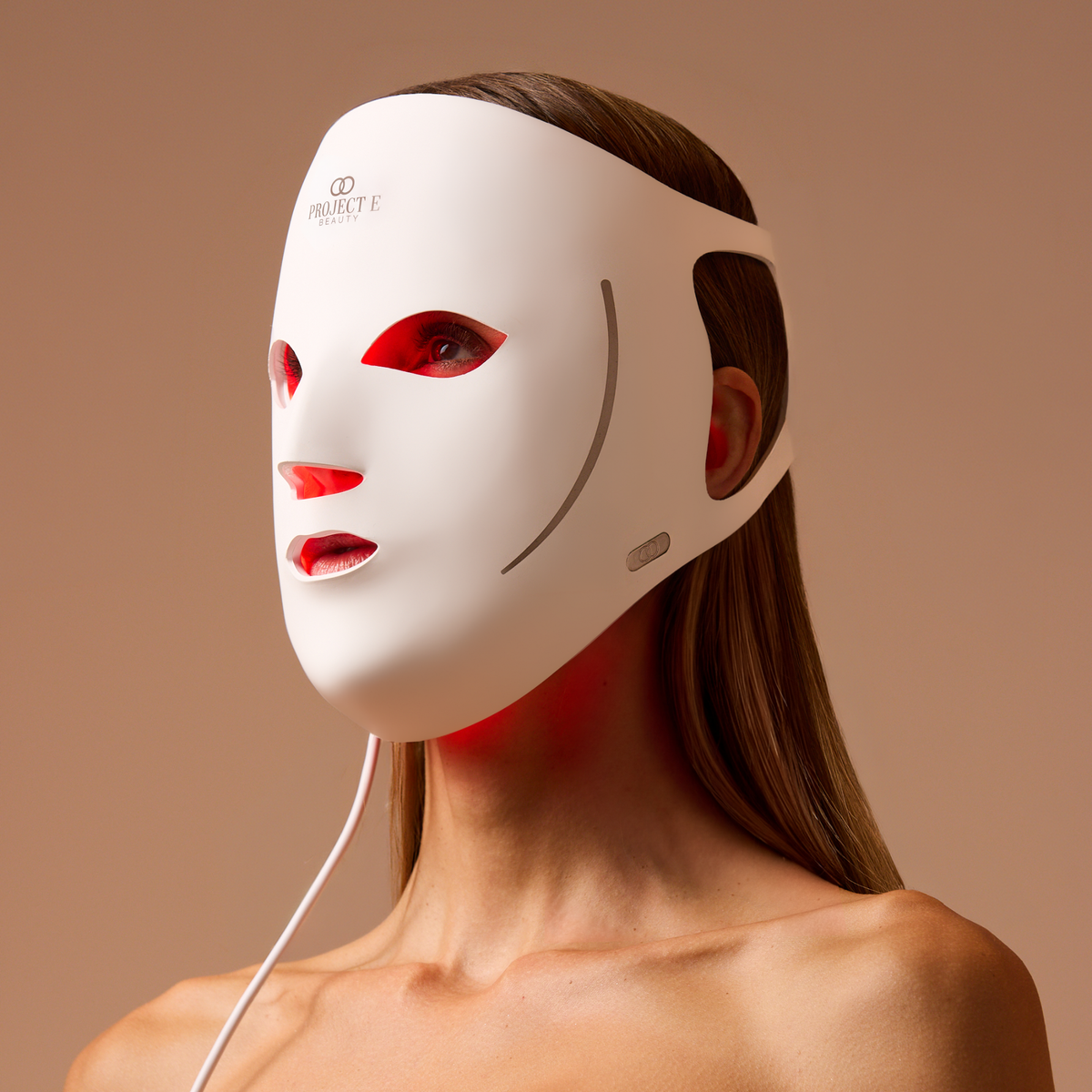 Woman wearing the white LumaLux Face V2 mask with red light visible inside