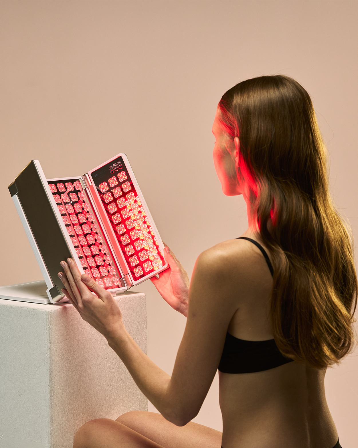 Woman using a foldable red light therapy panel for facial treatment